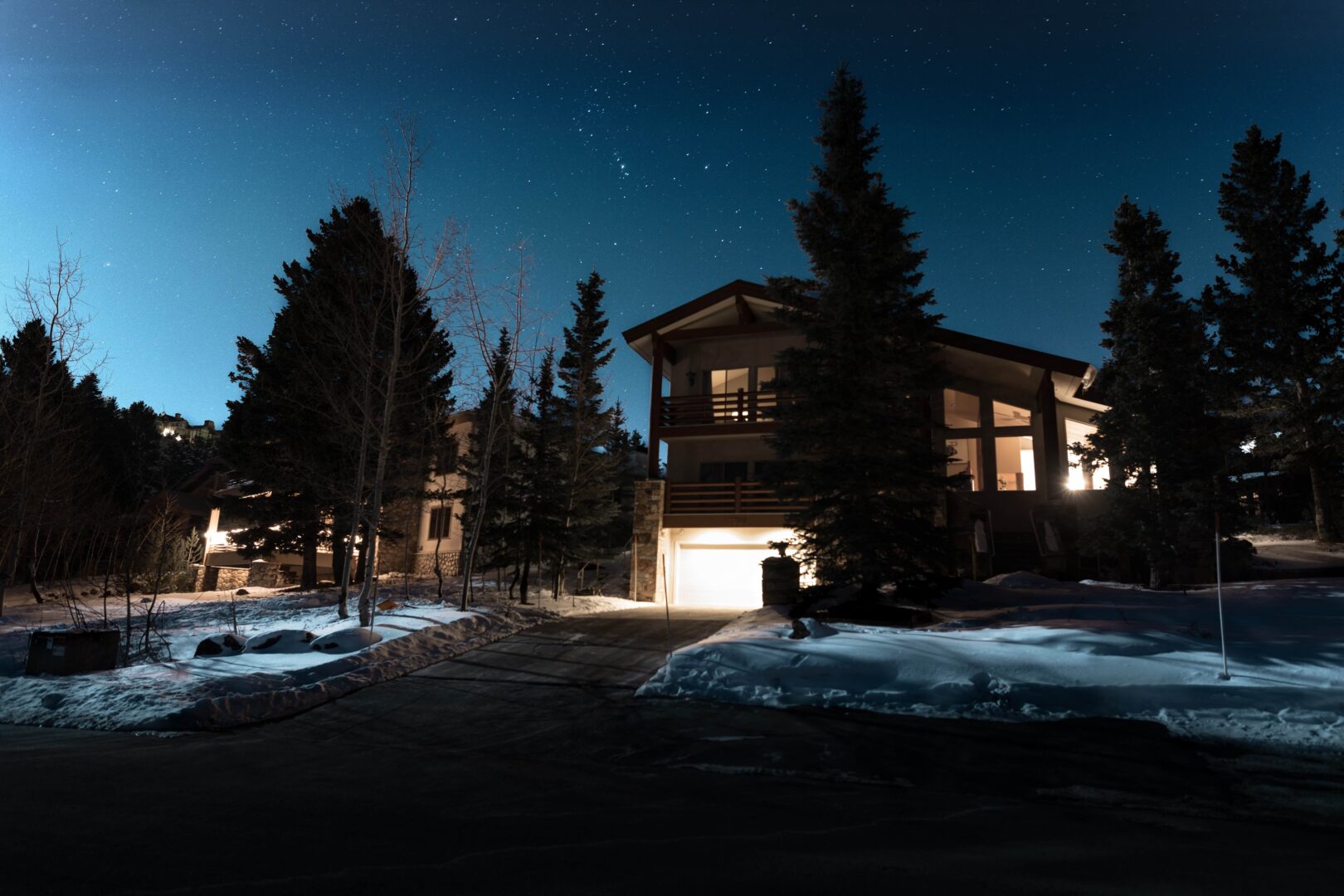 Big house with lights on at night with snow