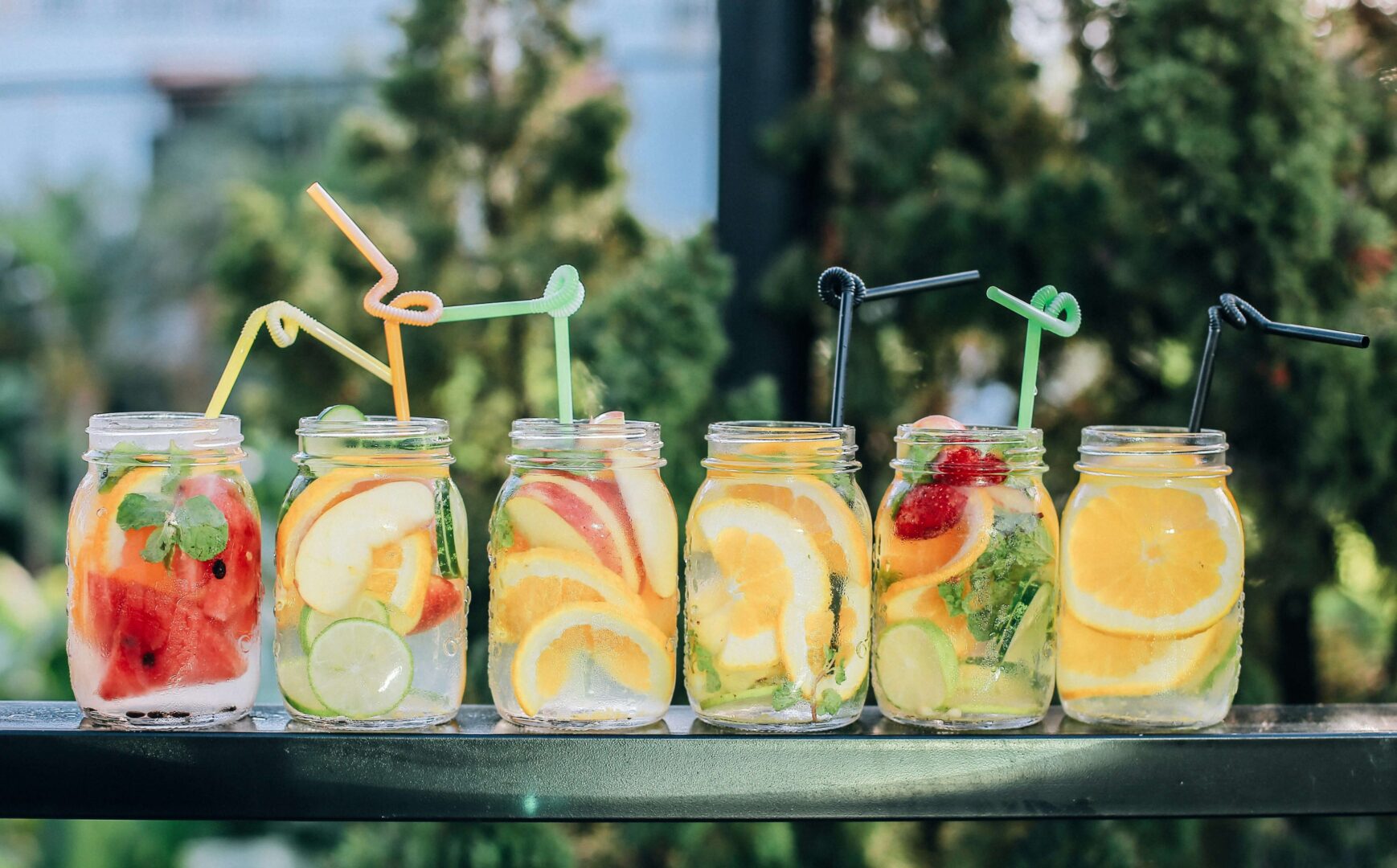 Photo of mason jars lined up, filled with tasty drinks.