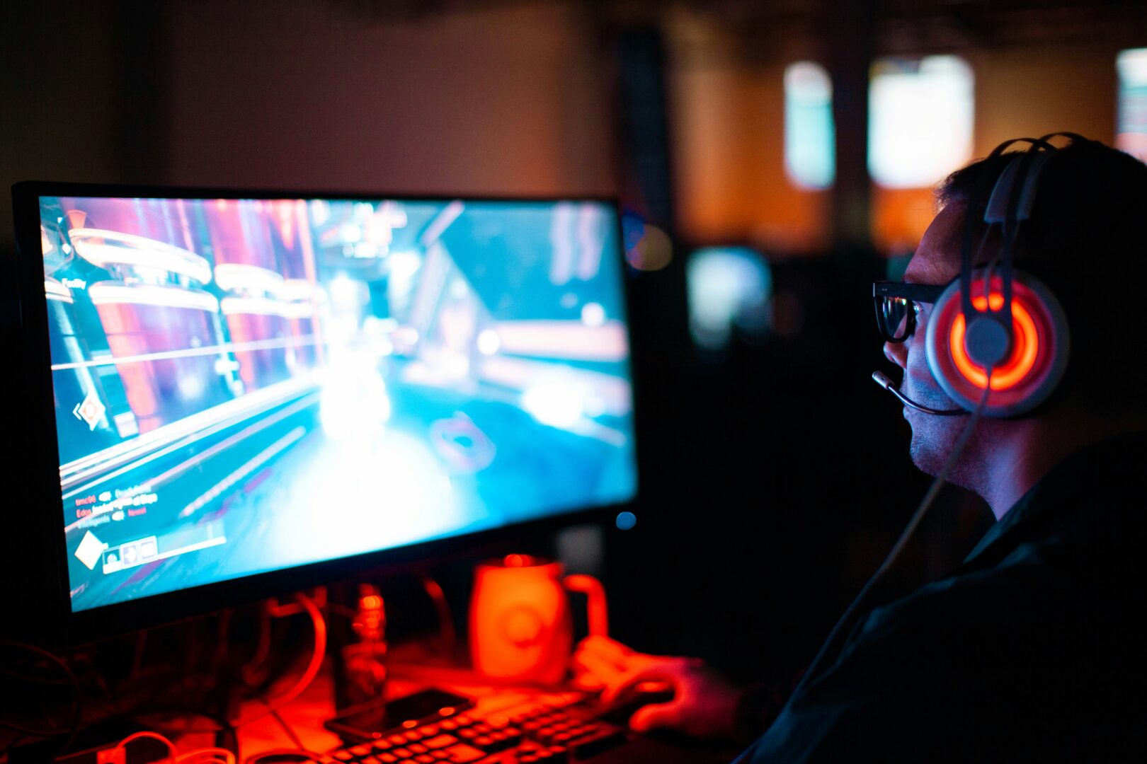 A man sitting at his desk with a headset on looking at a gaming screen