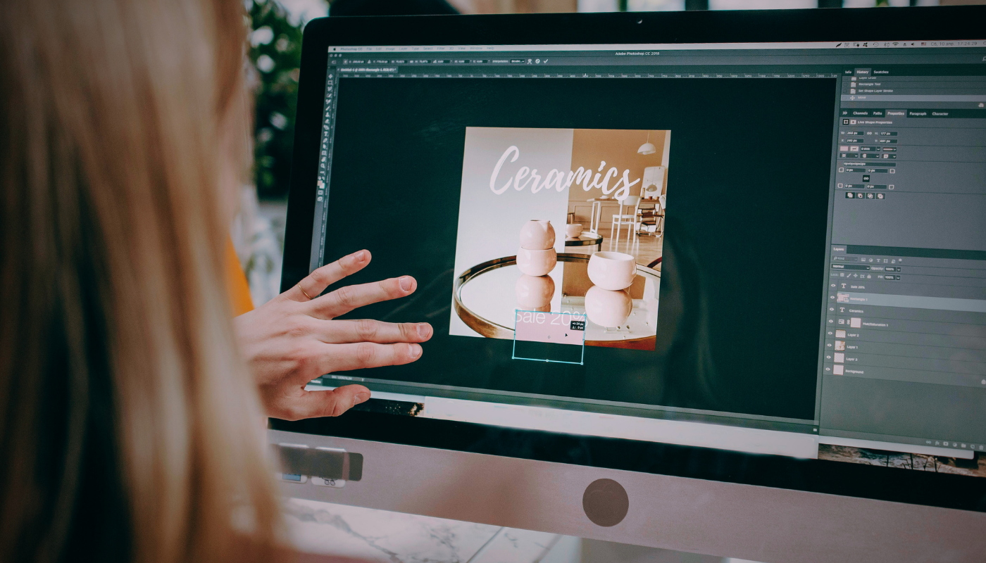 A designer working on a laptop with creative software visible on screen, illustrating the consolidation battle between Canva, Adobe and Figma for dominance over the creative workflow market.